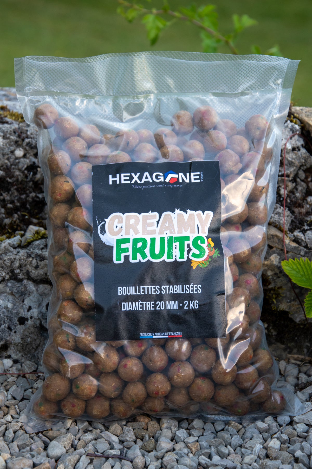 Sac transparent de bouillettes HEXAGONE «Creamy Fruits», billes brunes sur gravier.