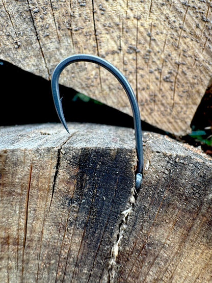 Hameçon à pointe recourbée, couleur bleu acier, posé sur bois